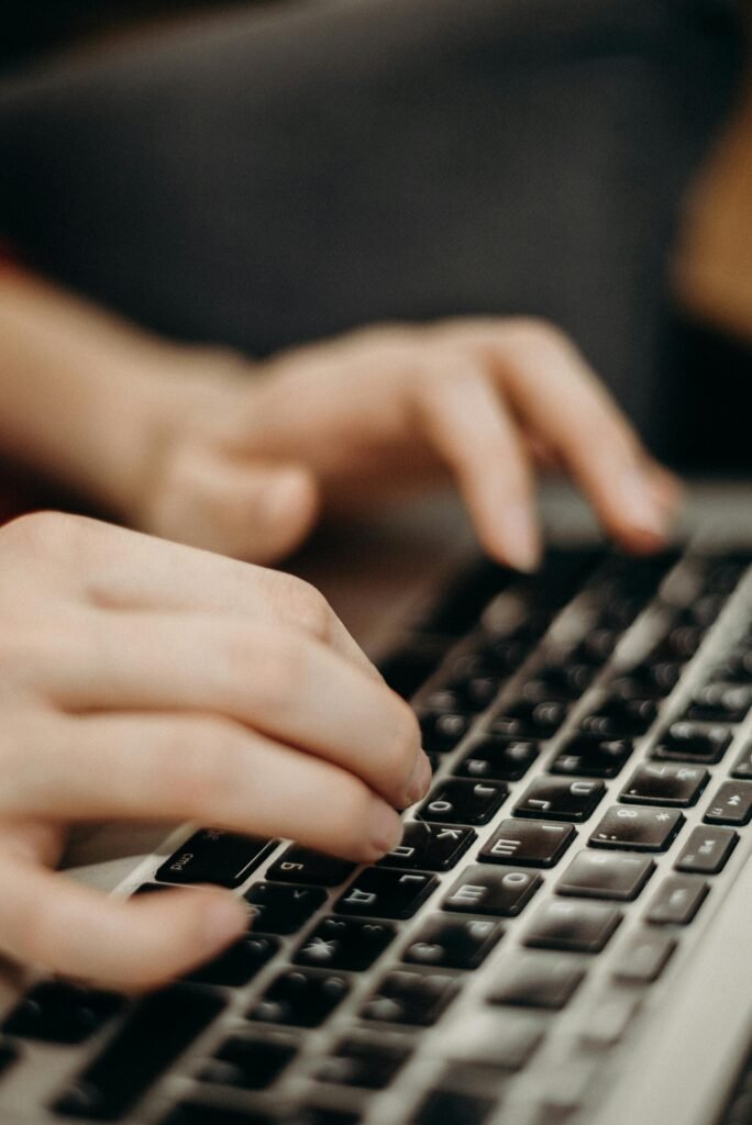 pexels-photo-3201478-3201478 Close-up shot of hands typing on a laptop keyboard in a work environment.